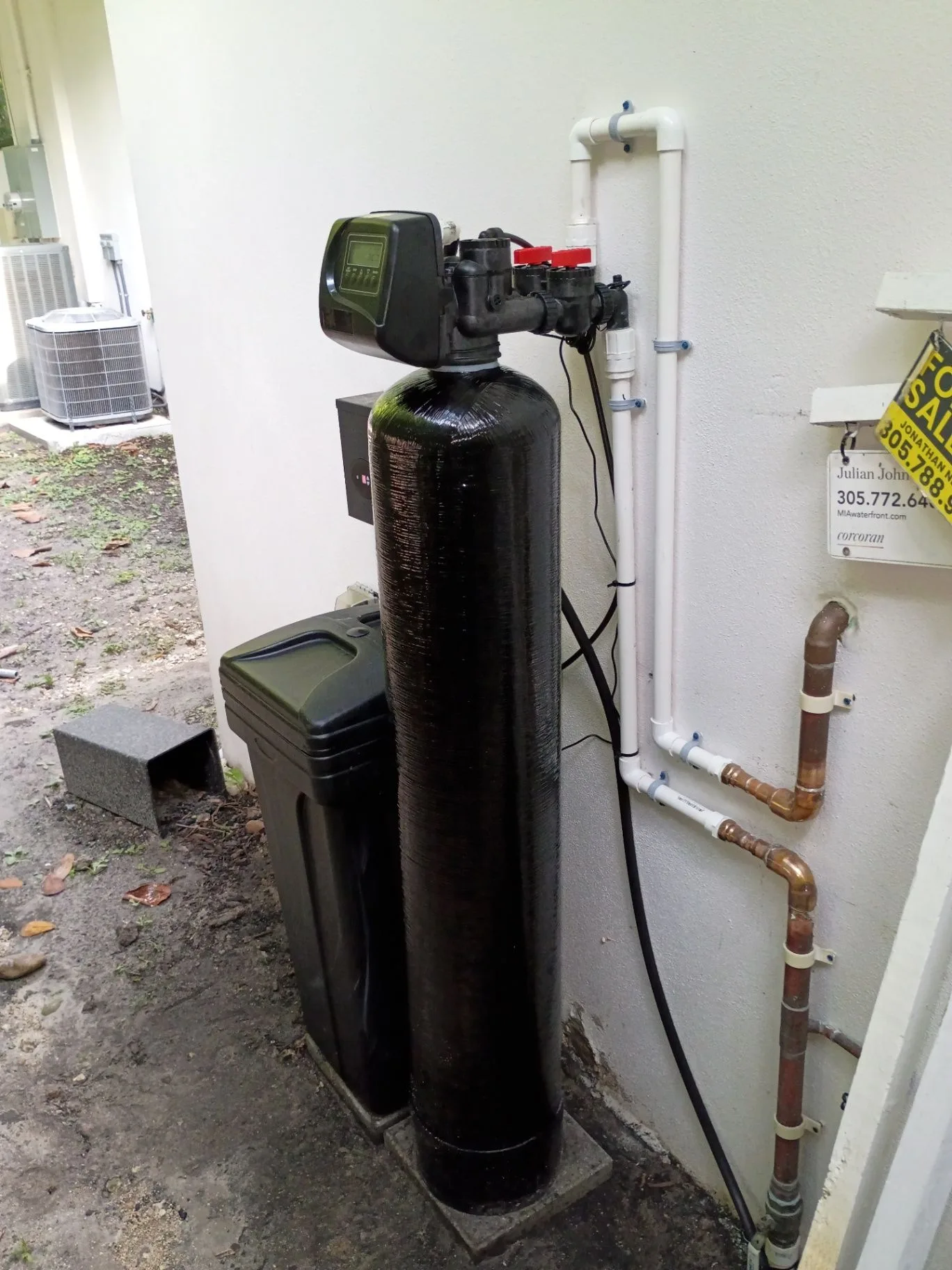Installed whole-home water softener beside a home exterior
